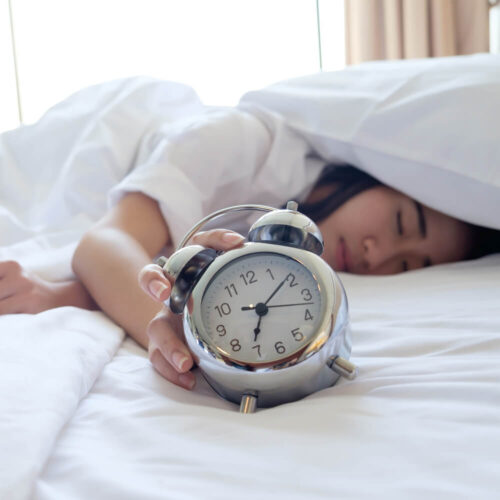 Woman sleeping in bed with an alarm clock